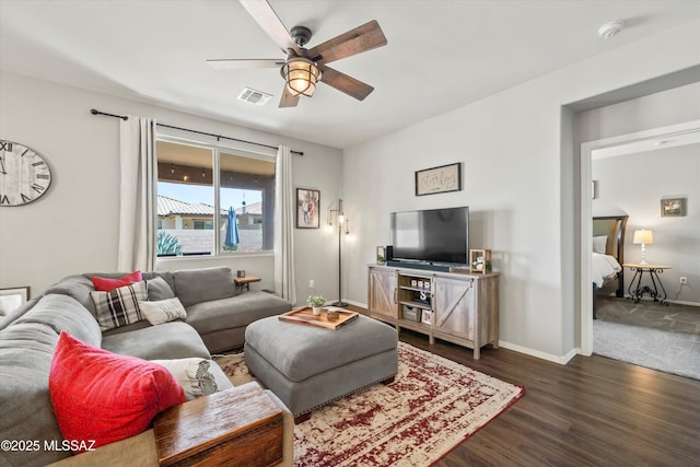 living area featuring ceiling fan, visible vents, baseboards, and dark wood-type flooring