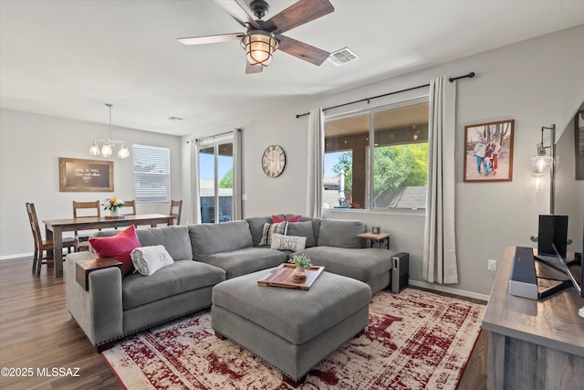 living room with visible vents, baseboards, ceiling fan with notable chandelier, and wood finished floors