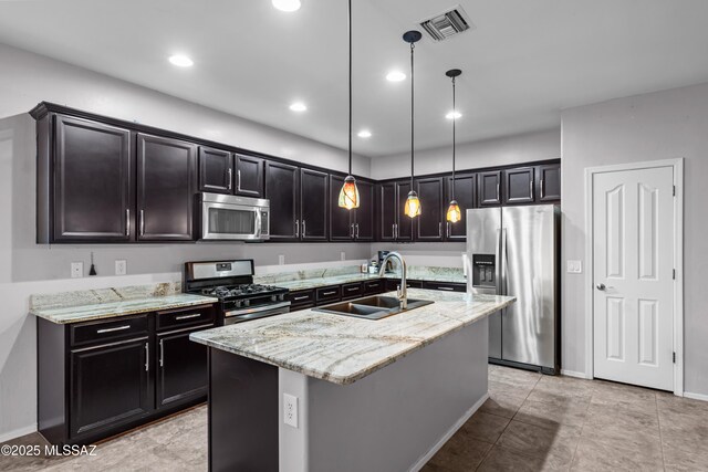 1020 E Wiley Squirrel Ln, Sahuarita, AZ 85629 - kitchen with pendant lighting, appliances with stainless steel finishes, light stone countertops, a sink, and an island with sink