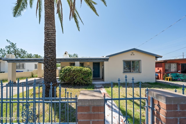 view of front of home with a gate, a fenced front yard, a front lawn, and stucco siding