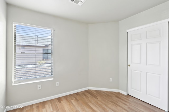 empty room featuring visible vents, baseboards, wood finished floors, and a healthy amount of sunlight