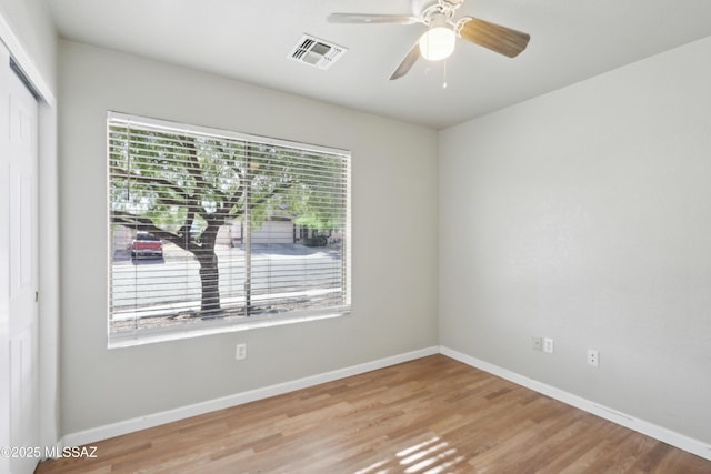 unfurnished room with visible vents, baseboards, plenty of natural light, and wood finished floors