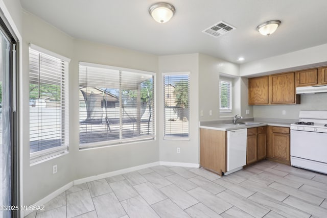 kitchen with visible vents, a sink, light countertops, under cabinet range hood, and white appliances