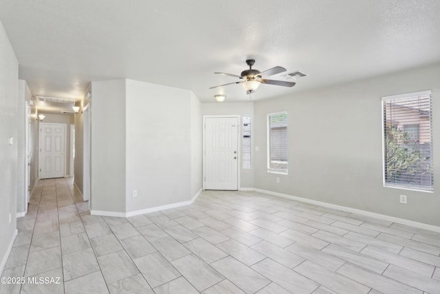 empty room featuring baseboards, ceiling fan, visible vents, and a healthy amount of sunlight