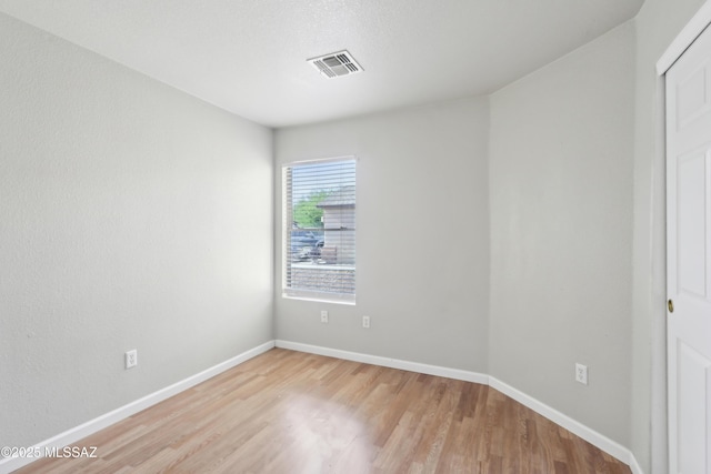 spare room with light wood-style floors, baseboards, and visible vents