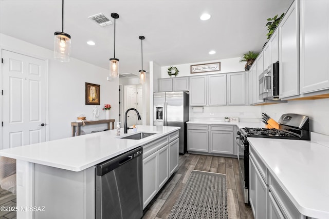 kitchen with visible vents, a kitchen island with sink, light countertops, a sink, and appliances with stainless steel finishes