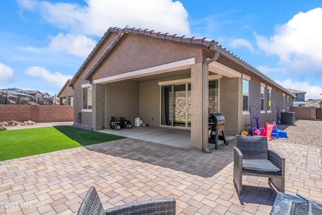 rear view of property with a patio, a fenced backyard, stucco siding, and a yard