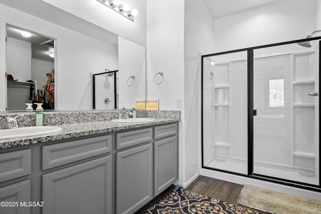 bathroom with a sink, double vanity, a stall shower, and wood finished floors