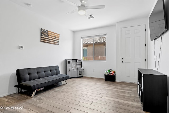 living area with baseboards, ceiling fan, light wood finished floors, and visible vents