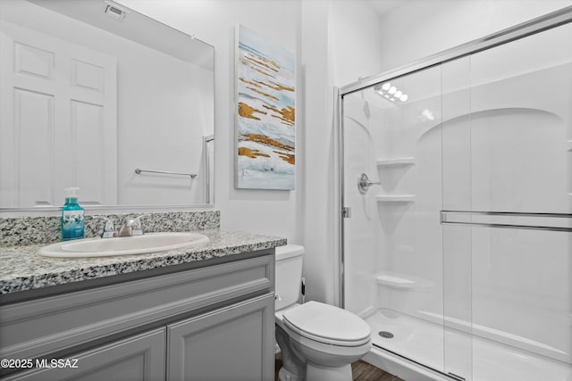 bathroom with a stall shower, toilet, and visible vents