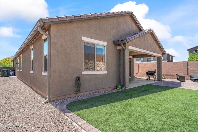 back of house featuring fence, a patio, stucco siding, and a yard