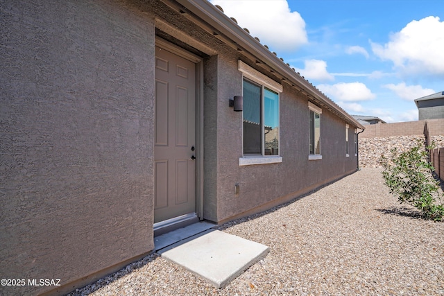 entrance to property with stucco siding and fence