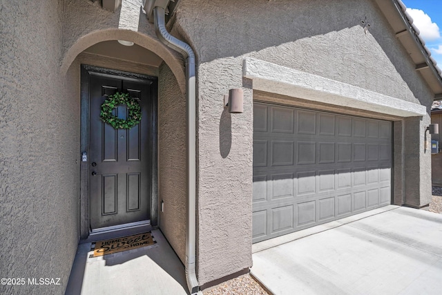 entrance to property featuring driveway and stucco siding