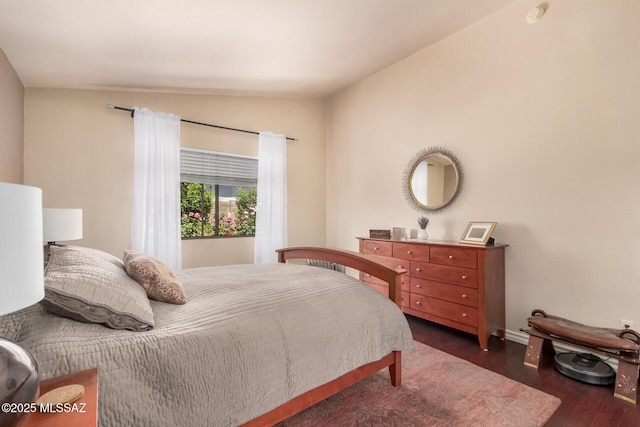 bedroom with vaulted ceiling, wood finished floors, and baseboards