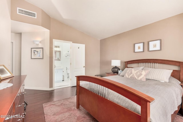 bedroom with dark wood-style floors, vaulted ceiling, baseboards, and ensuite bathroom