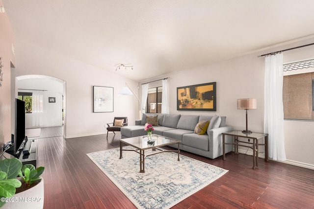 living area with arched walkways, dark wood-style flooring, and baseboards