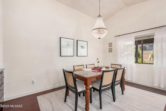 dining area featuring a chandelier, wood finished floors, baseboards, and high vaulted ceiling