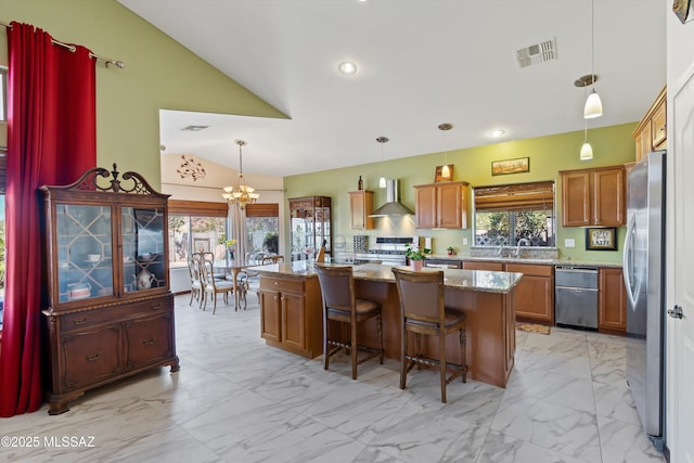 39930 S Mountain Shadow Dr, Tucson, AZ 85739 - kitchen featuring wall chimney exhaust hood, appliances with stainless steel finishes, a chandelier, brown cabinetry, and vaulted ceiling