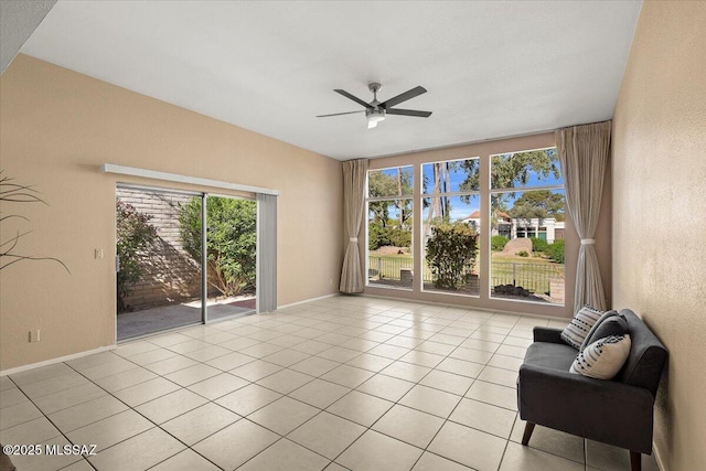 empty room with light tile patterned floors, baseboards, a textured wall, and a ceiling fan