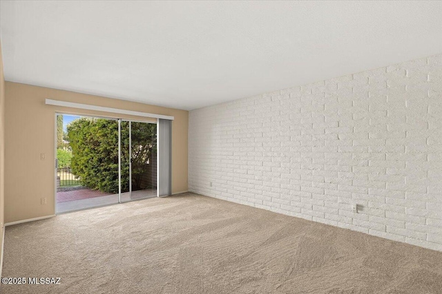 carpeted spare room featuring brick wall