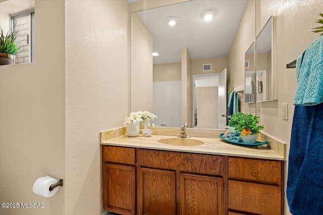 bathroom featuring vanity, a textured wall, and visible vents