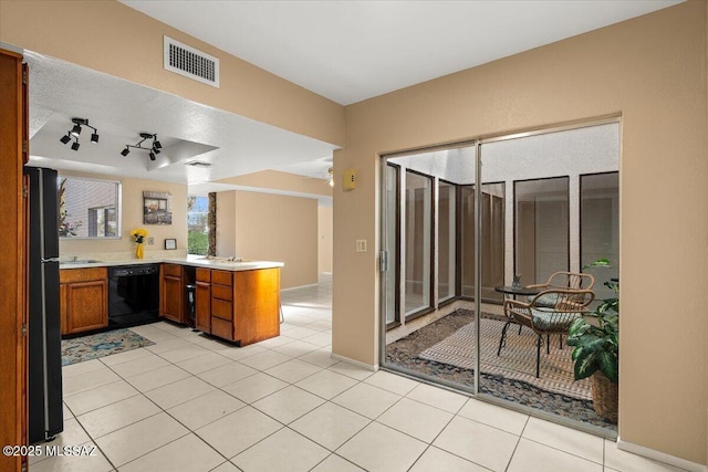 kitchen featuring visible vents, brown cabinets, light countertops, black appliances, and a peninsula