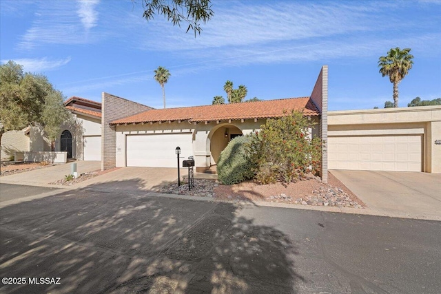 single story home with a garage, stucco siding, driveway, and a tile roof