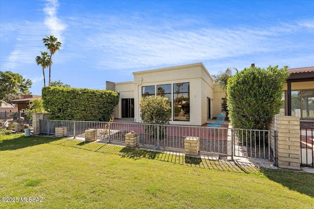 back of house with a lawn, stucco siding, and fence
