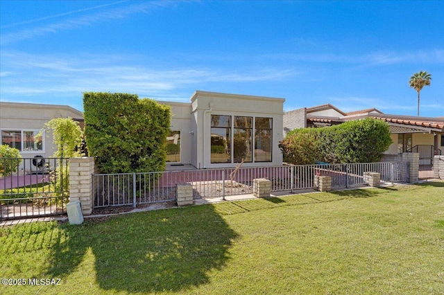 back of property with a lawn, fence, and stucco siding