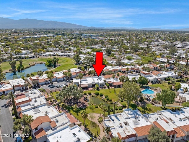 drone / aerial view featuring a water and mountain view, view of golf course, and a residential view