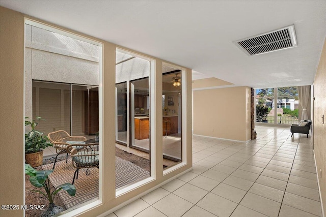 interior space with baseboards, floor to ceiling windows, light tile patterned floors, and visible vents