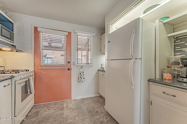 kitchen with dark countertops, white appliances, extractor fan, white cabinetry, and tasteful backsplash