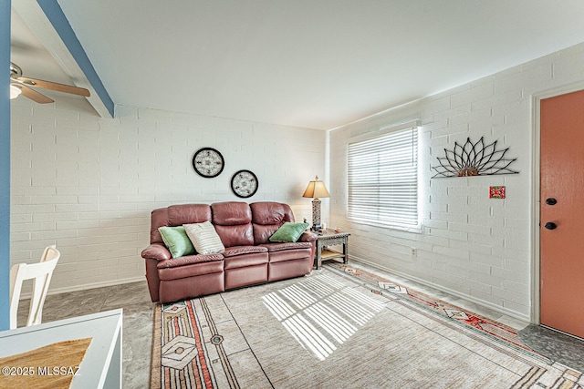 living area featuring ceiling fan and brick wall
