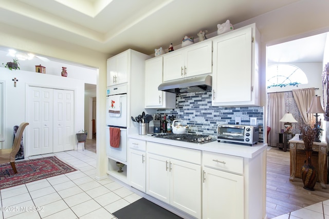 21 Kachina, Rio Rico, AZ 85648 - kitchen featuring stainless steel gas cooktop, a toaster, light countertops, under cabinet range hood, and white double oven