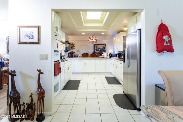 21 Kachina, Rio Rico, AZ 85648 - kitchen with white cabinets, light tile patterned flooring, appliances with stainless steel finishes, light countertops, and a tray ceiling
