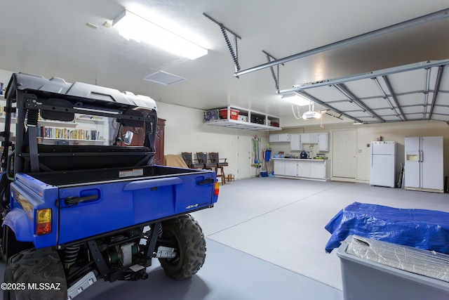 21 Kachina, Rio Rico, AZ 85648 - garage featuring freestanding refrigerator, a garage door opener, and white fridge with ice dispenser