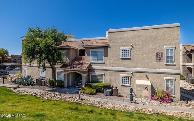 view of front of house with cooling unit, a chimney, a tile roof, and stucco siding