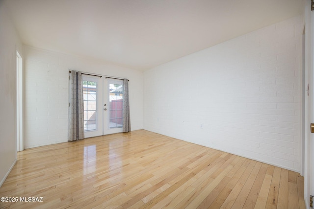 390 N Silverbell Rd, Tucson, AZ 85745 - unfurnished room with light wood-style flooring, brick wall, and french doors