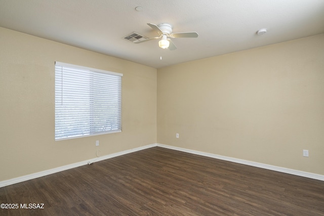 unfurnished room featuring dark wood-style flooring, a ceiling fan, baseboards, and visible vents