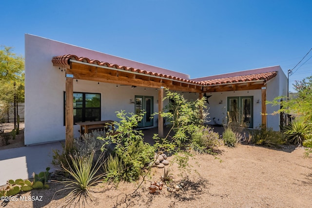 view of front of property featuring french doors, stucco siding, and a tiled roof