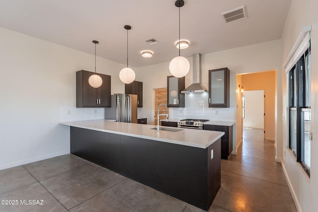 kitchen with wall chimney range hood, tasteful backsplash, finished concrete floors, a sink, and appliances with stainless steel finishes