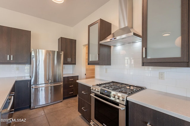 kitchen with backsplash, stainless steel appliances, wall chimney exhaust hood, and dark brown cabinets