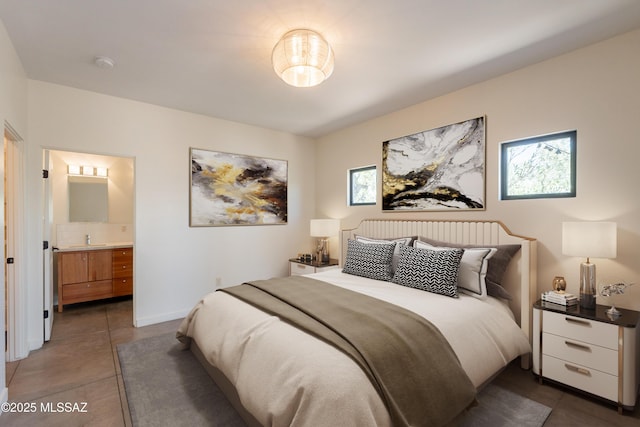 bedroom featuring a sink, dark tile patterned floors, and ensuite bath
