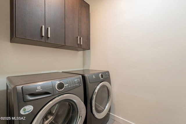 clothes washing area with baseboards, independent washer and dryer, and cabinet space