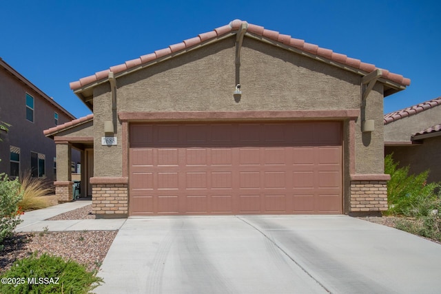 7688 S Via Perfecta, Tucson, AZ 85756 - view of front facade with a tiled roof, brick siding, and an attached garage