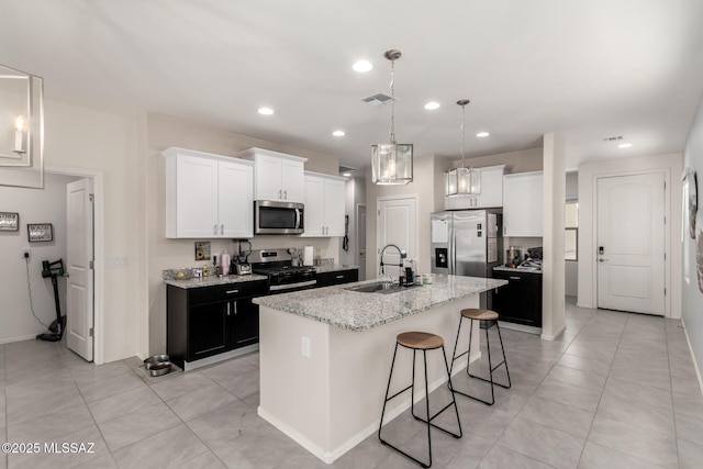 7688 S Via Perfecta, Tucson, AZ 85756 - kitchen with stainless steel appliances, a sink, a breakfast bar area, an island with sink, and white cabinetry