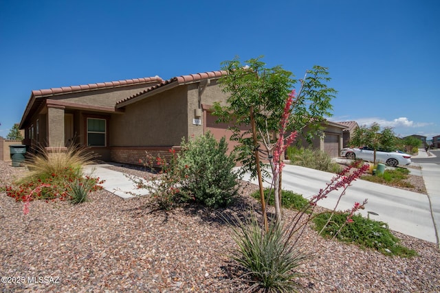 7688 S Via Perfecta, Tucson, AZ 85756 - view of side of home featuring an attached garage, stucco siding, brick siding, and a tile roof