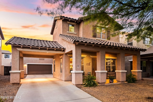 mediterranean / spanish-style house featuring covered porch, stucco siding, a tiled roof, concrete driveway, and an attached garage