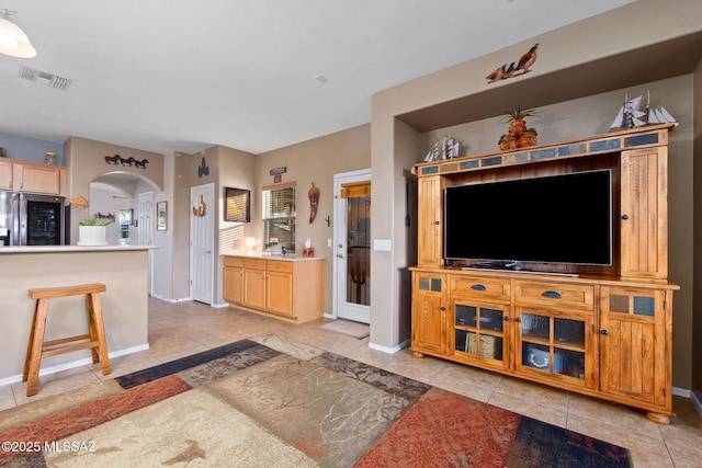 living area with arched walkways, baseboards, visible vents, and light tile patterned floors