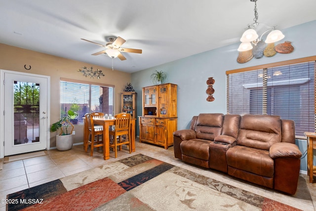 living room with light tile patterned flooring and ceiling fan with notable chandelier